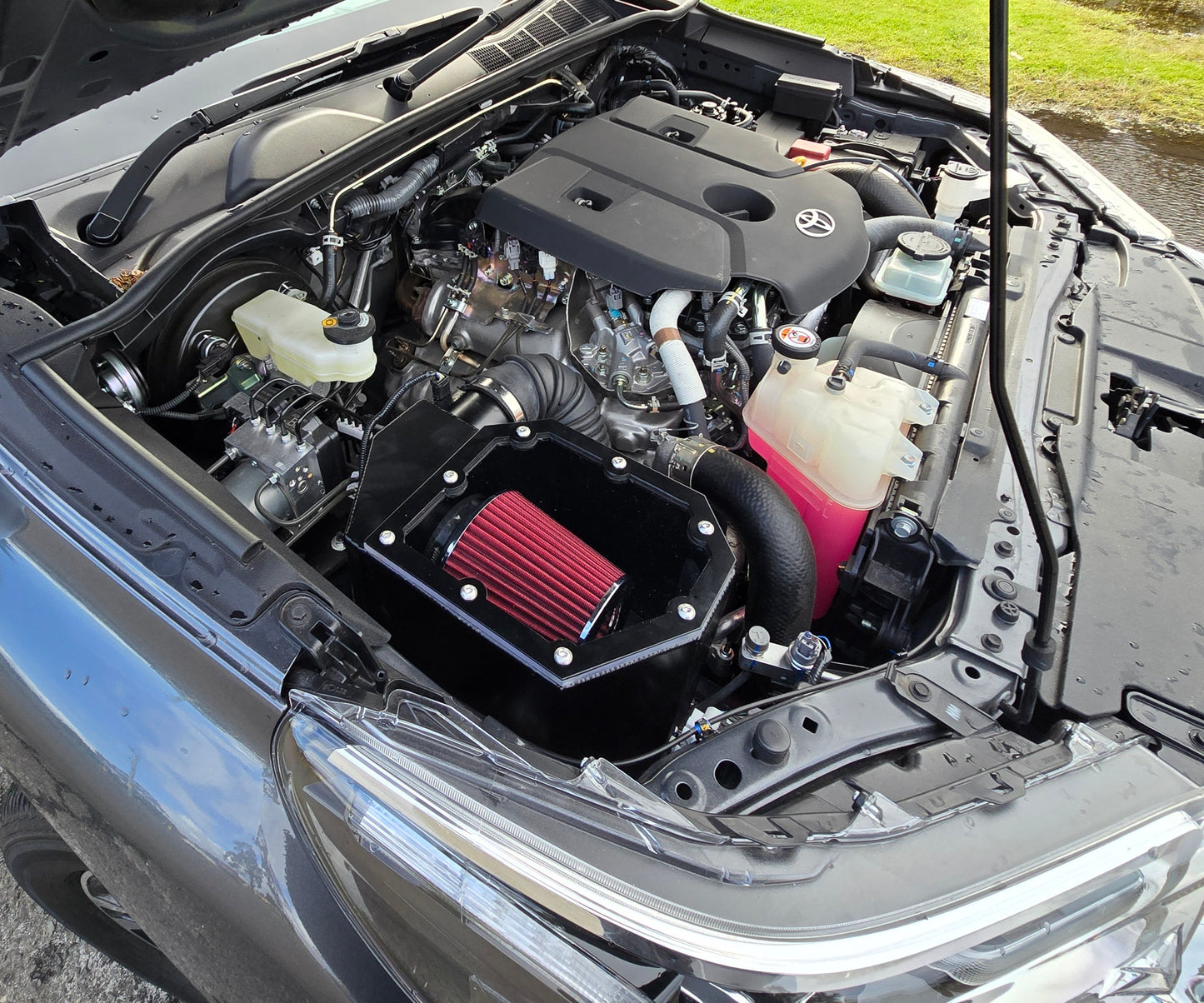 Open car hood displaying a clean engine with a prominent red air filter.