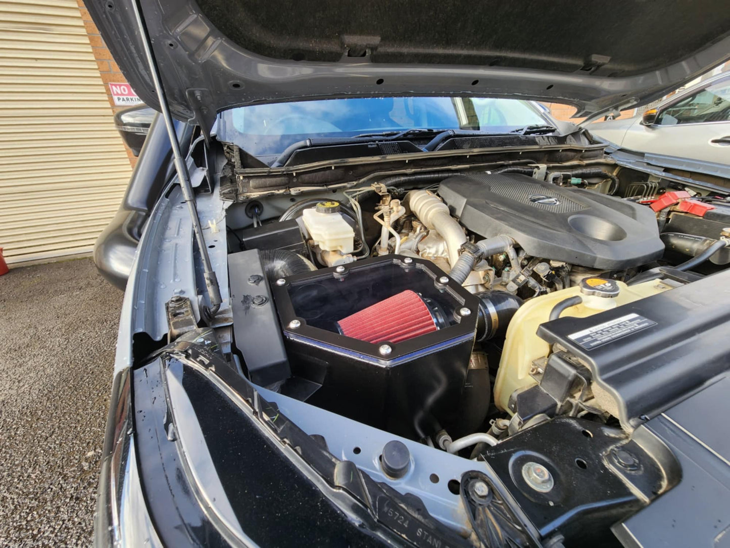 Black pickup truck with its hood open, revealing the engine.